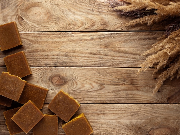 Bars of natural soap with dried flowers on a wooden table.