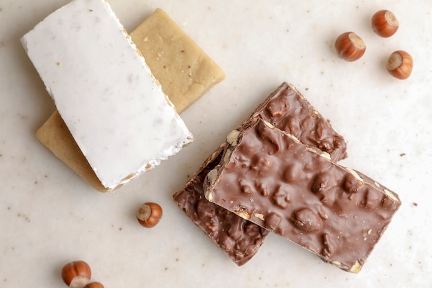 Bars of sweet chocolate nougat with walnuts on a white table