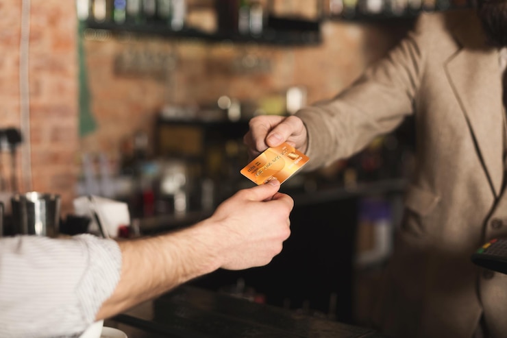 Photo bartender accepting credit card at counter in bar. cashless payment, modern technologies in every day life, copy space