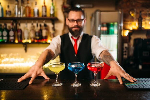 Бармен за барной стойкой показывают алкогольные коктейли
