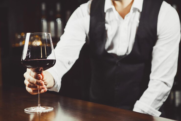 Photo bartender at the bar with a glass of red wine closeup