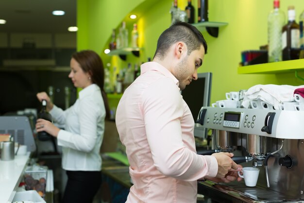 Bartender and barista working at bar