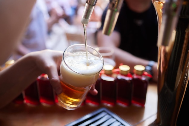 bartender hand at beer tap pouring a draught beer in glass serving in a restaurant or pub