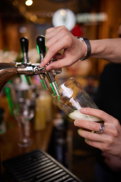 Photo bartender hand at beer tap pouring a draught beer in glass serving in a restaurant or pub