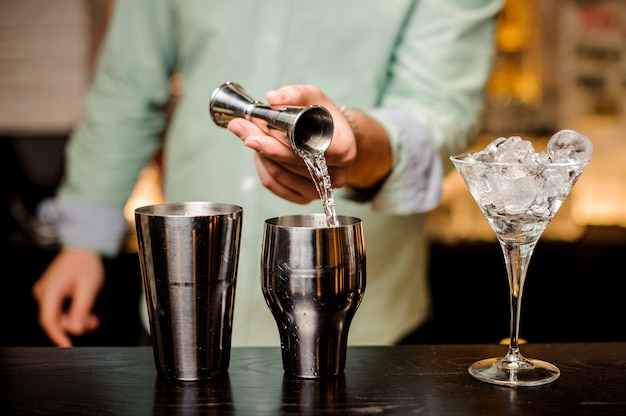 Фото Бармен руки наливает напиток в джиггер, чтобы приготовить коктейль крупным планом