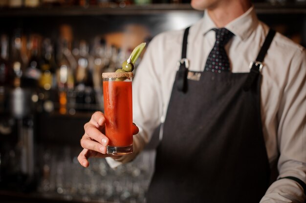 Bartender holding a bloody mary cocktail with olives and celery