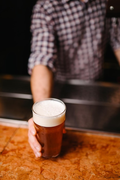 Barista con in mano un bicchiere di birra al bar