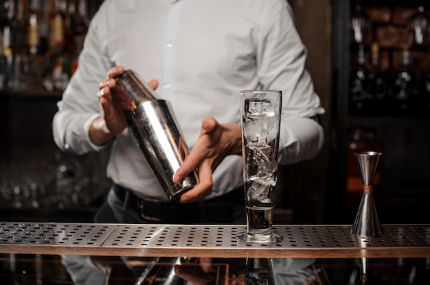 Photo bartender holding a steel shaker at the bar counter