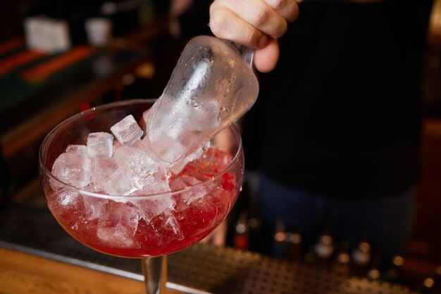 Bartender is making cocktail at bar counter at night club close up concept about service and beverages