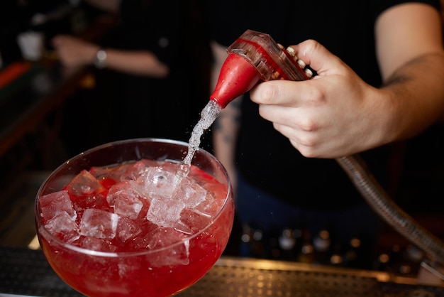 Bartender is making cocktail at bar counter at night club Close Up Concept about service and beverages