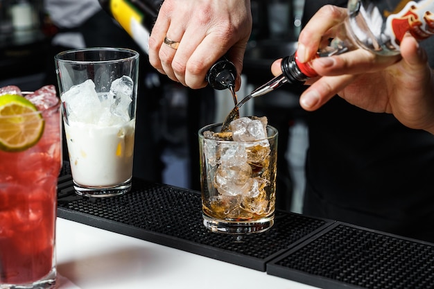 Bartender is making cocktail at bar counter at night club