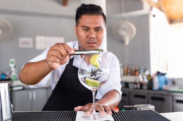 Il barista sta preparando un cocktail al bancone del bar.