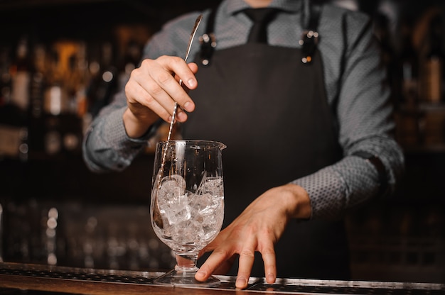 Bartender is making make a cocktail with ice