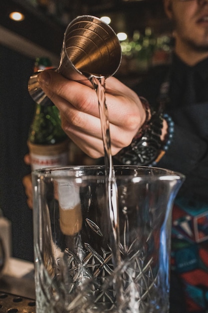 Photo the bartender is pouring liqueur in to stir the glass