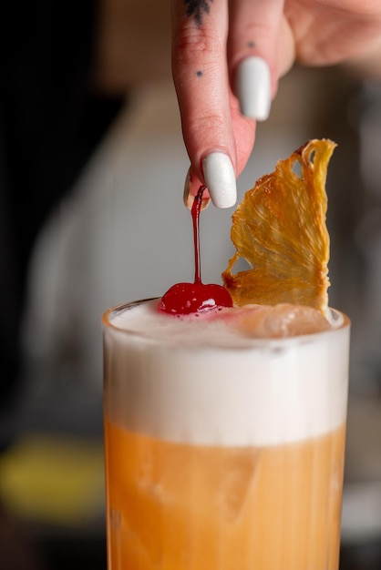 Bartender is preparing a cocktail at the bar Decorating a cocktail cherry ready cocktail in a glass