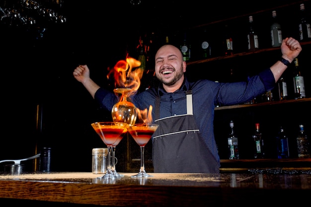 The bartender makes hot alcoholic cocktail and ignites bar