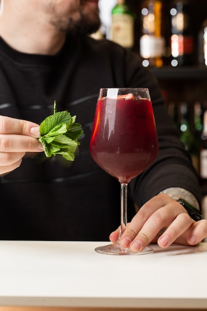 Бармен делает красную сангрию в итальянском ресторане коктейль Сангрия с красным вином на баре размыто