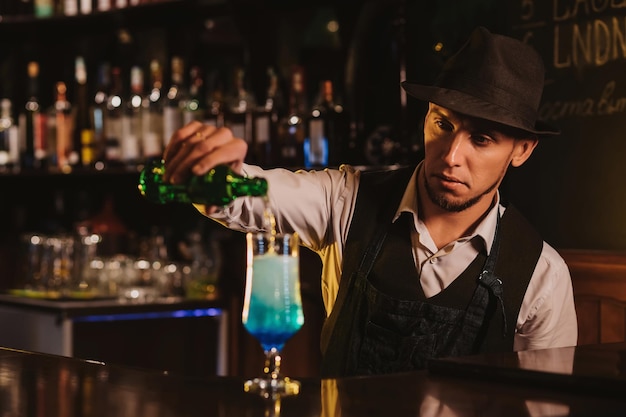 Bartender mixes a Blue Lagoon cocktail in a glass at bar counter