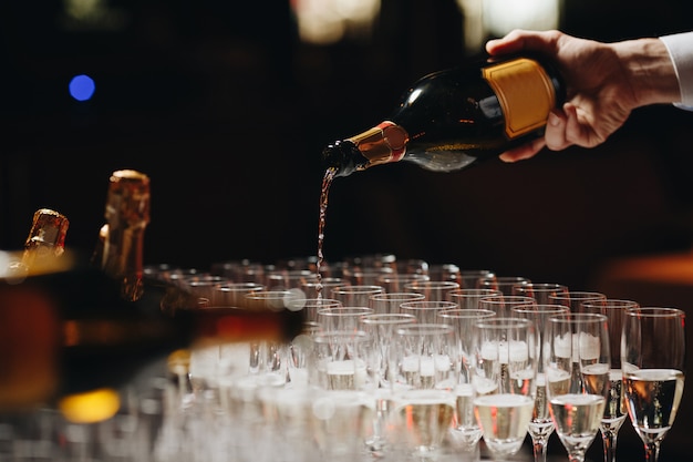Бармен наливает шампанское или вино в бокалы на столе на торжественной церемонии на открытом воздухе