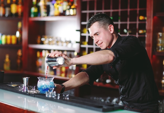 Bartender pouring fresh cocktail in fancy glass