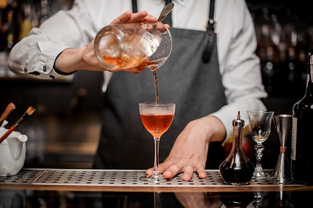 Bartender pouring fresh sweet alcoholic drink into the cocktail glass