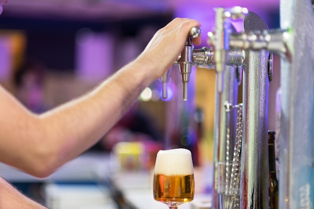 Bartender pouring lager beer in a glass. 