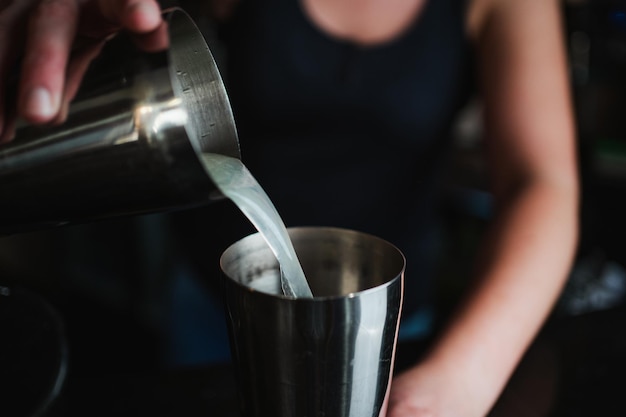 Bartender pouring lemon juice into a cocktail shaker to prepare a pisco sour