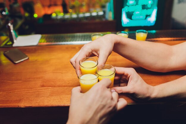 Bartender pouring strong alcoholic drink into small glasses on bar, shots.