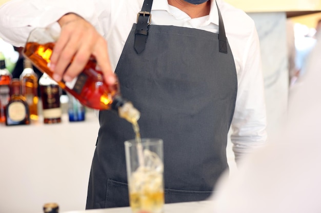 bartender pouring whisky on glass outdoor bar