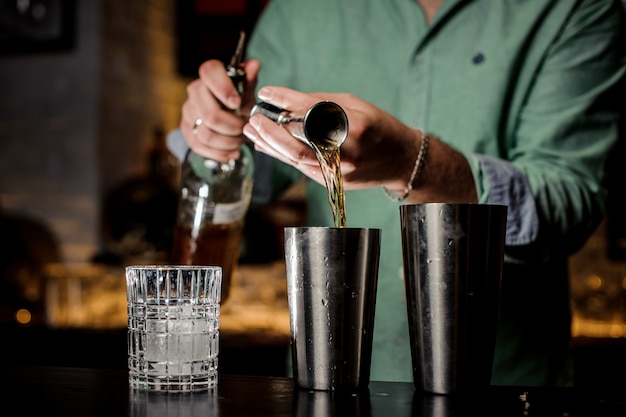 The bartender pours alcohol in a bar no face