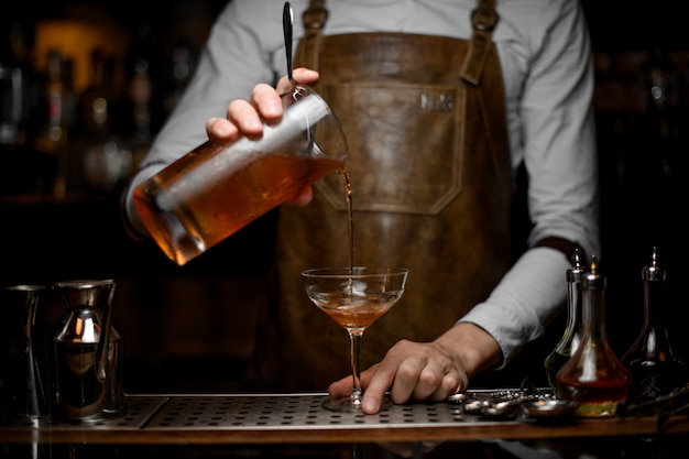 Bartender pours alcohol cocktail from the strainer