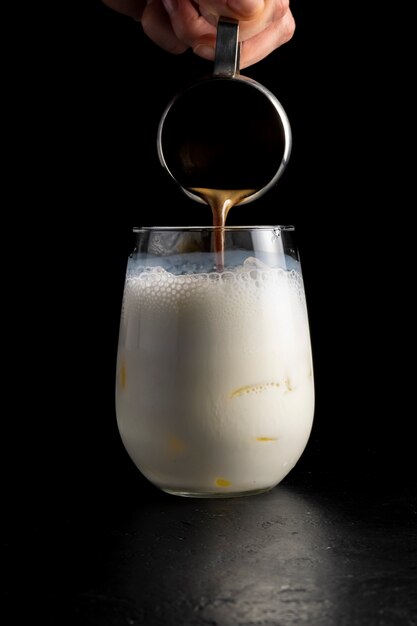 The bartender pours coffee into ice latte milk froth.