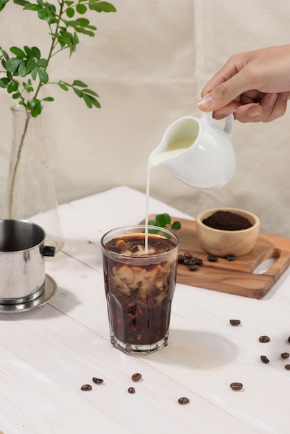 Bartender pours milk into glass of coffee