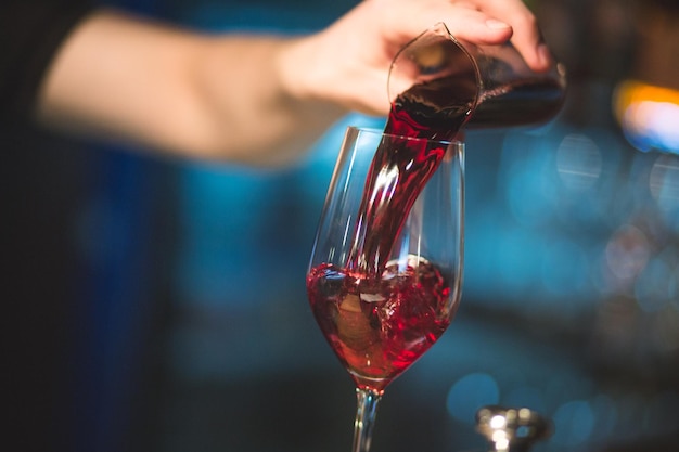 Foto il barista versa il vino rosso in un bicchiere. copia spazio sullo sfondo