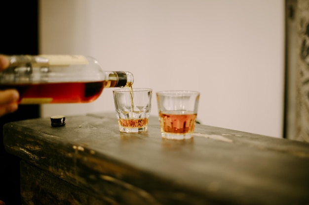 The bartender pours whiskey into glasses on the bar counter, soft focus