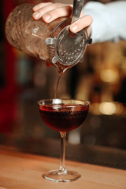 Photo the bartender prepares a cocktail for the client at the bar counter