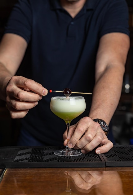 A bartender prepares a cocktail with a cherry on top