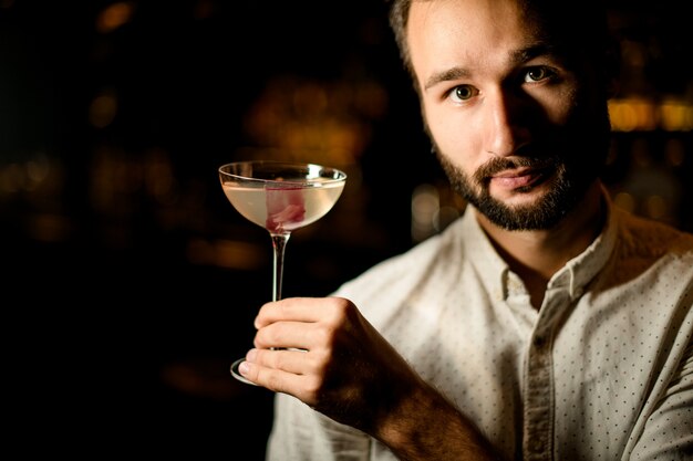 Bartender presenting a cocktail in the glass decorated with pink ice cube