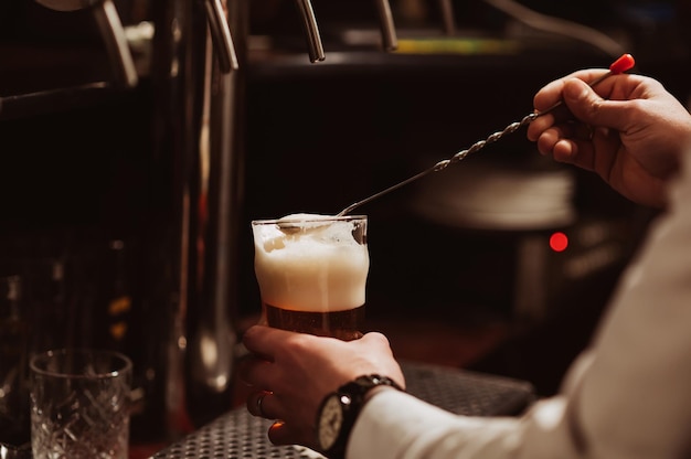 Bartender removes the foam from the beer from the glass in the bar