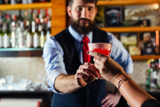 Бармен подает коктейль для клиента в баре