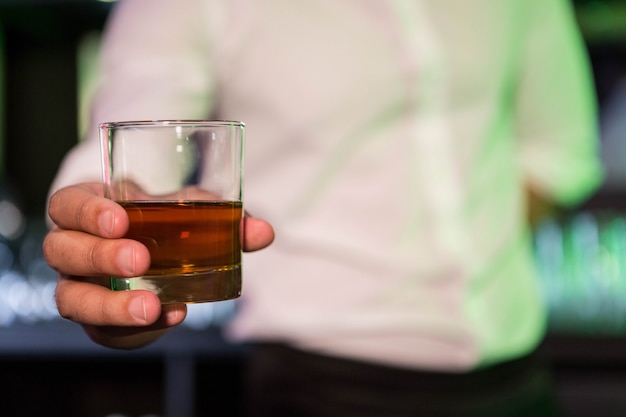 Bartender serving a glass of whiskey in bar