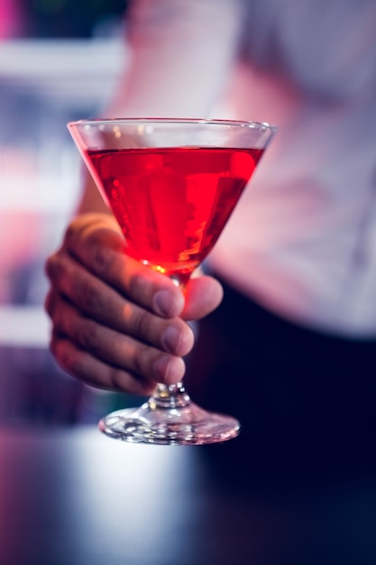 Bartender serving a red martini in bar