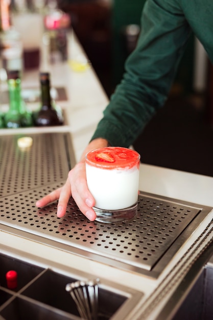 Barista che serve un cocktail alla fragola in un bicchiere di rocce