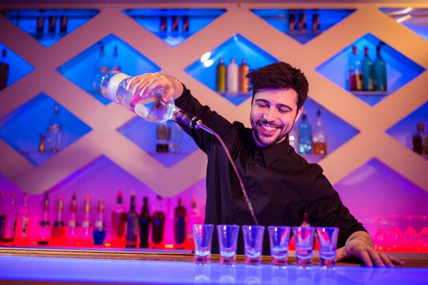 Bartender smiling while pouring alcohol in shot glass
