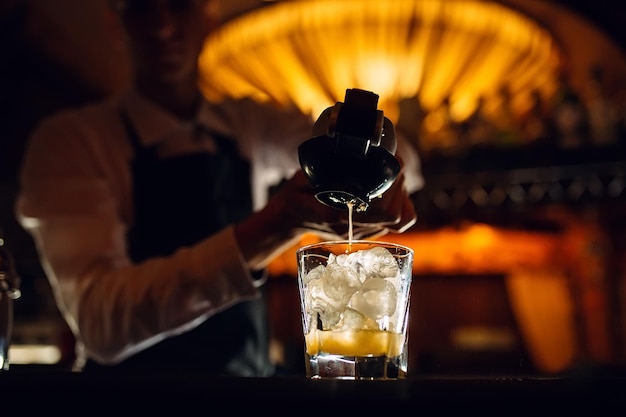 The bartender squeezes citrus juice into a cocktail.