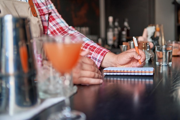 Foto barista in piedi al bancone del bar a prendere appunti