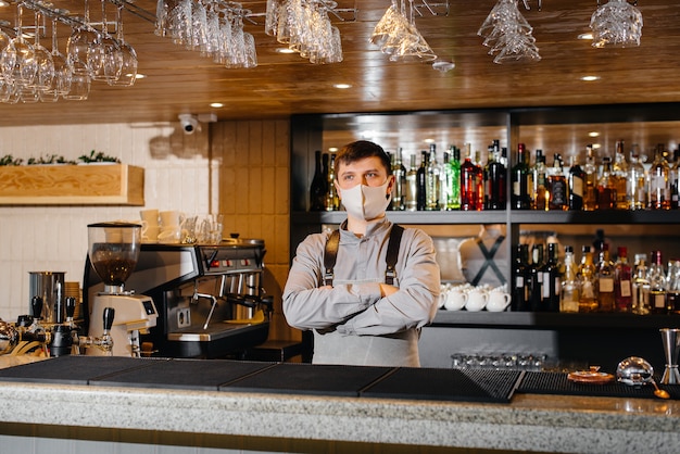 The bartender stands with his arms crossed behind the bar in a modern restaurant.