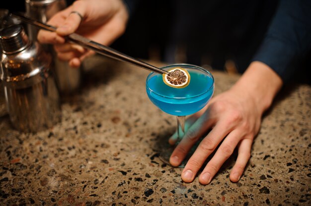 Bartender supplements the Blue Lagoon alcohol cocktail