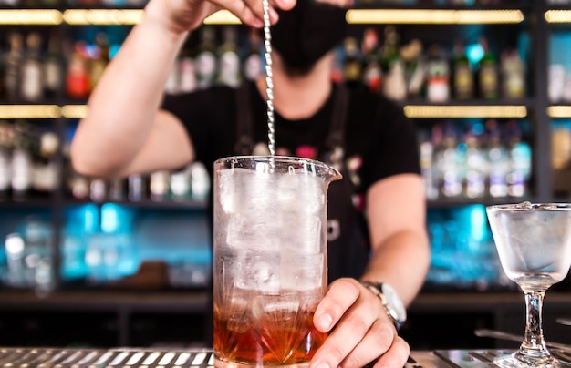 Бармен барной ложкой размешивает лед в стакане, чтобы он быстрее охладился Горизонтальное фото