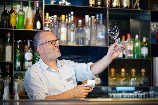 The bartender wipes out the wine glass at work.